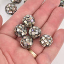 Hand holding six round, patterned beads with a blurred background
