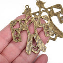 Two bronze-colored metal charms in the shape of a thunderbird, held between fingers, with a textured and rustic appearance.
